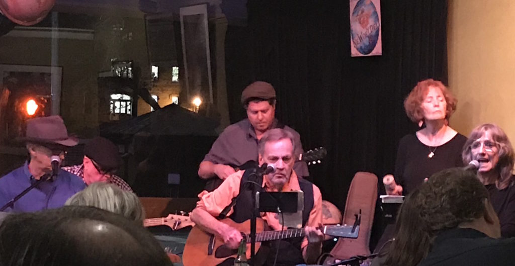 brady coleman sitting in chair, tshirt of gainsville 8 reunion.
5 members of melancholy ramblers band