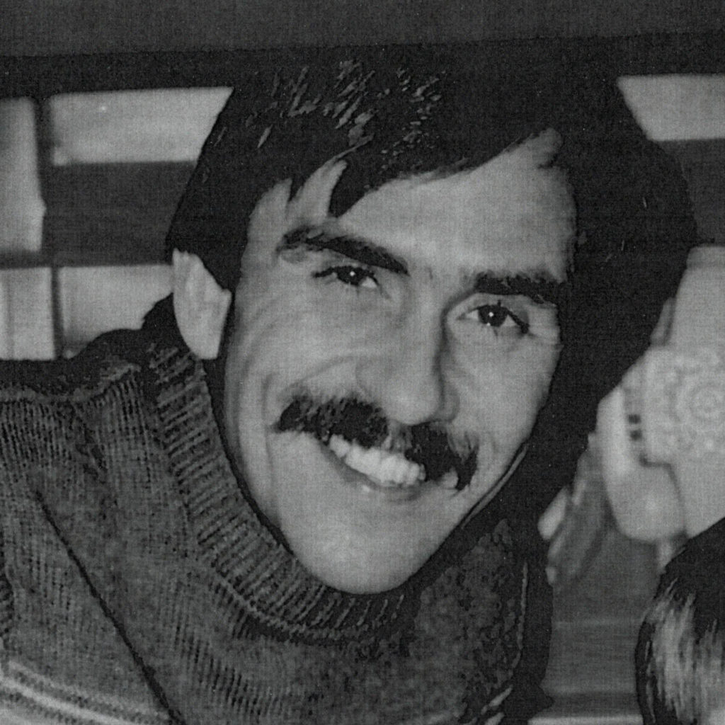 John Vlcek smiling in black and white